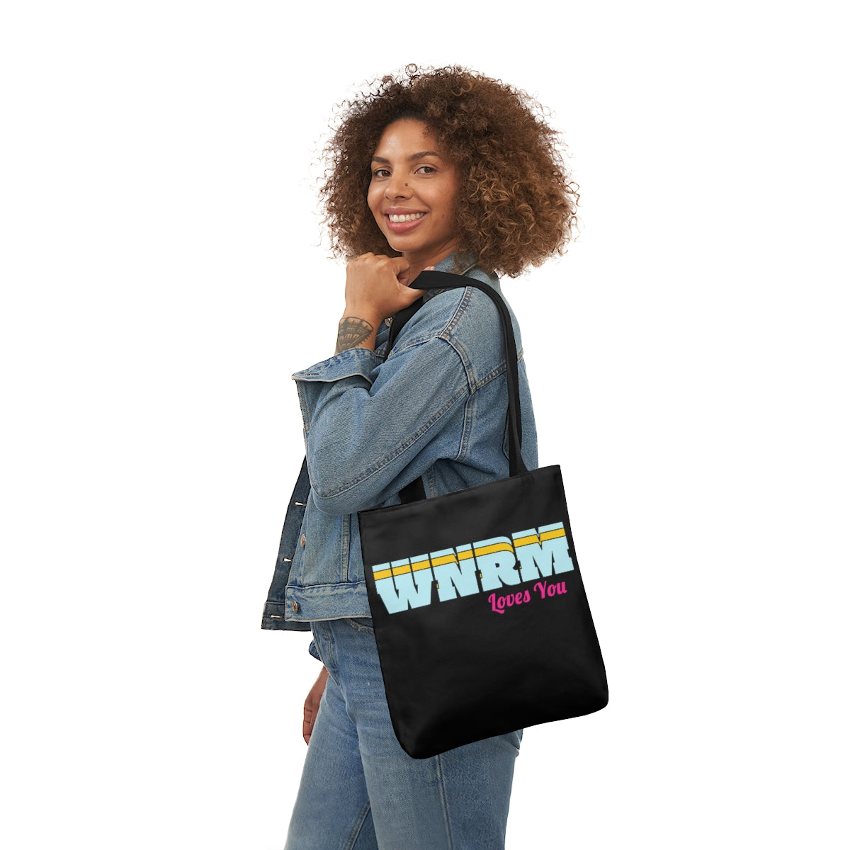 Cool girl holding a WNRM Loves You Polyester Canvas Tote Bag, with jeans on on a white background