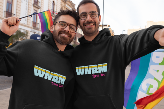 Couple wearing WNRM Loves You Unisex Heavy Blend™ Hooded Sweatshirt, at gay pride fest