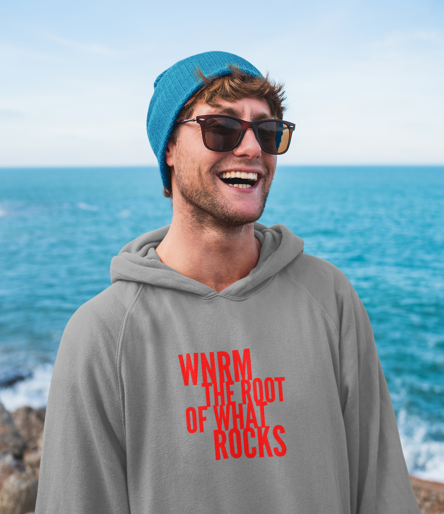 Surfer dude OG WNRM Logo Sweatshirt with a blue hat on the beach