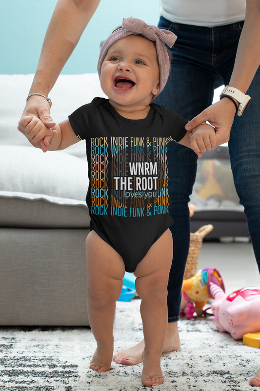 Cute baby girl wearing a WNRM The Root Loves You Colors bodysuit while learning to walk 
