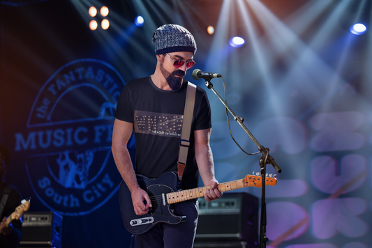 Musician wearing a WNRM Name In Lights Tee while playing guitar on stage under the spolights