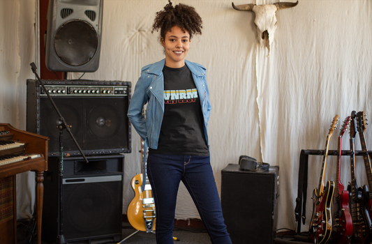 Cool girl wearing a WNRM The Root Logo Tee Women's Triblend Tee, in music studio, next to guitars and amps