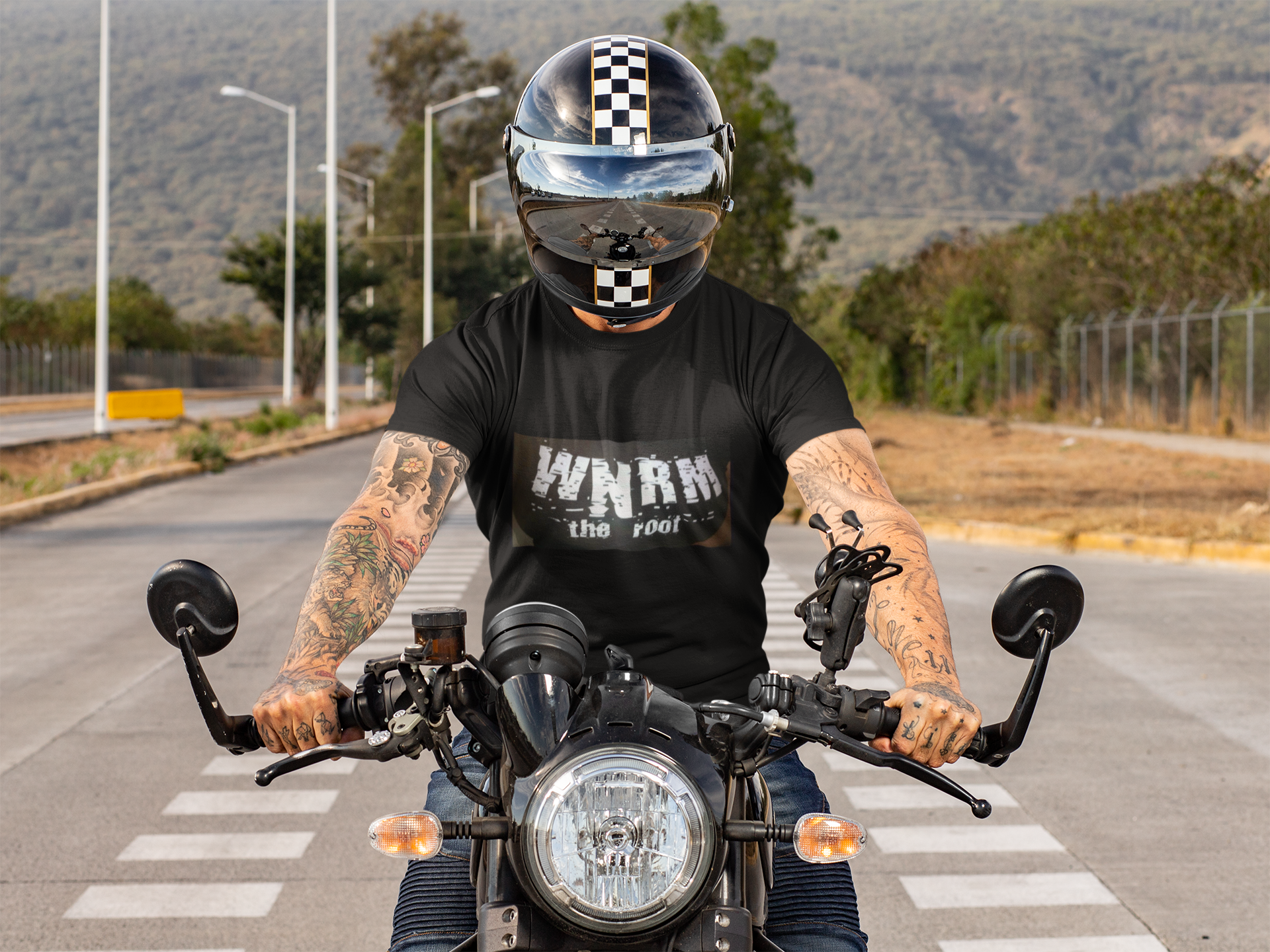 Man on a motorcycle wearing a OG WNRM Boob Tee with a helmet on, on a California road
