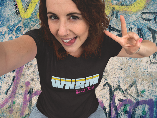 Funny face girl wearing a WNRM Loves You Women's Softstyle Tee, in front of graffiti art